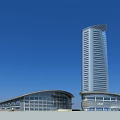 Modern Urban Architecture With Tall Glass Tower And Curved Low Rise Building Under Blue Sky