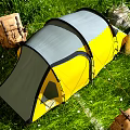 Yellow And Gray Camping Tent Set Up On Green Grassland With Mountain Rocks And Backpacks