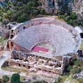 Ancient Circular Theater Ruins Surrounded by Trees and Rocky Archaeological Site