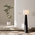 Modern Floor Lamp with Black Stand and White Shade Beside Green Plant on Light Wall