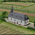 Aerial View Of Green Countryside Farmland With Historic Church And Lush Trees