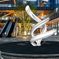 Modern Urban Commercial Street With Glass Facades Sculpture Escalators And Evening Pedestrians
