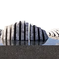 Art Installation Made Of Stone Wood With Curved Structure Vertical Pieces And Water Reflection