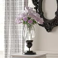 Transparent Glass Vase With Purple Roses Against White Patterned Curtain And Black Carved Mirror