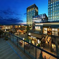 Illuminated Commercial Street Night View With Modern High Rise Buildings Luxury Shops And Pedestrians