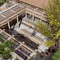 Outdoor Courtyard With Wooden Roof Stone Paved Floor Benches People Relaxing And Green Plants