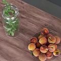 Clear Glass Bottle With Green Plant And Plate Of Peaches On Wooden Tabletop