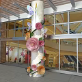 Decorative Column With Colorful Paper Flowers And Butterflies In Glass Facade Building Entrance
