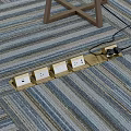 Golden Floor Socket Panel with Multiple Sockets Floor Mounted on Striped Carpet and Plug Inserted