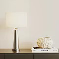 Silver Cone Base Table Lamp with White Fabric Shade and Textured Vase on Books