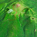 Aerial View of Green Mountainous Volcanic Terrain With Red Trail and Crater