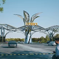 Modern Entrance Gate With Leaf Shaped Metallic Structure Loden Sign Surrounding Trees Vehicles And Pedestrians
