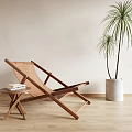 Wooden Lounge Chair Featuring Side Table Books Palm Plant In White Planter On Wooden Floor