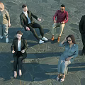Diverse Group of People Standing and Sitting on Stone Pavement in Formal Attire