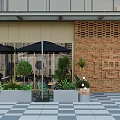 Modern Cafe Outdoor Seating Area With Glass Facade Brick Wall Black Umbrellas And Green Plants