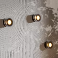 Three Round Glass Wall Lamps on Textured White Wall with Warm Light and Leaf Shadows