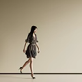 A Woman Walking Against Beige Background Wearing Dark Dress High Heels and Long Black Hair
