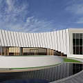 Modern Building With Curved White Facade Large Glass Windows Circular Pool Reflection And Blue Sky