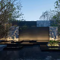 Modern Building Exterior Wall With Stone Cladding Water Feature Landscaped Greenery And Accent Lighting