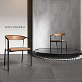 Modern Leisure Chair with Brown Cushion Black Metal Frame Round Platform and Gray Wall