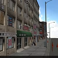 Vibrant Commercial Street With Multi Story Buildings Shop Signs Street Lamps And Traffic Cones