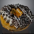 Fresh Glazed Orange Donut With White Drizzle And Black Chocolate Crumbs