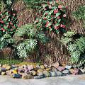 Green Plant Wall With Purple Flowers Hanging Vines And Diverse Green Plants On Stone Ground