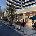Bustling Commercial Street Featuring Modern High Rise Buildings Outdoor Cafes Trees Shops And Pedestrians