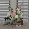 Pink and White Blooms in Glass Vase with Perfume Bottles Candles and Window Blinds