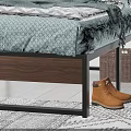 Double Bed with Metal Frame Light Green Geometric Bedspread Striped Pillows Brown Boots and Green Plant in Bedroom Interior