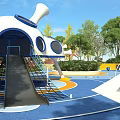 Modern Children's Playground With Blue Floor Central Tree Colorful Structures And Green Plants