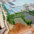 Aerial View of Modern School Campus Buildings With Green Rooftops Surrounding Roads and Sports Field