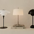 Three Modern Table Lamps With Stylish Shades Placed On Stack Of Books