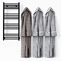 Three Comfortable Gray Robes Hanging Next To Black Towel Rack
