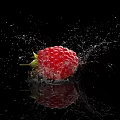 Close Up Fresh Juicy Raspberry with Splashing Water Droplets on Black Background