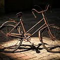 Rusty Bicycle With Weathered Frame On Brick Paved Ground Under Sunlight