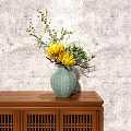 Green Ceramic Vase With Yellow Flowers And Green Branches On Wooden Cabinet Against Gray Wall