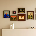 Diverse Framed Artworks on Beige Wall with White Candle and Books on Shelf 3d model