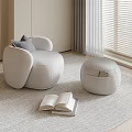 White Accent Chair With Gray Cushion And Ottoman On Light Rug Near Window With Books