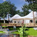 Scenic Camping Site With White Tents Wooden Deck Natural Stream Surrounded By Trees