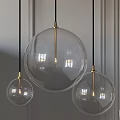Three Modern Pendant Lights With Transparent Glass Globes And Golden Metal Accents