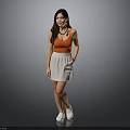 Woman in Orange Tank Top White Skirt and White Shoes Standing Against Gray Background