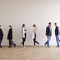 Group of people walking indoors on wooden floor with light colored wall background