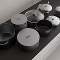 Various Sizes And Shapes Of Cookware Including Lidded Pots And Pans On Black Countertop