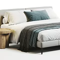 Double Bed With White Bed Sheet Gray And Blue Pillows And Wooden Round Side Table