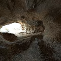 Natural Cave Scenery With Sunlight Streaming Through Top Opening And Rough Rock Formations