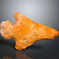 Vibrant Orange Natural Stone with Irregular Shape and Textured Surface Displayed on Dark Background