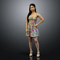Woman in colorful floral dress against black background with white high heels and hand on hip