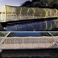 Modern Woven Curved Bridge Over Water With Evening Lighting And Green Surroundings