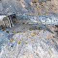 Stone Tunnel Entrance in Mountainous Terrain With Rocks Snow Patches and Slope Path
